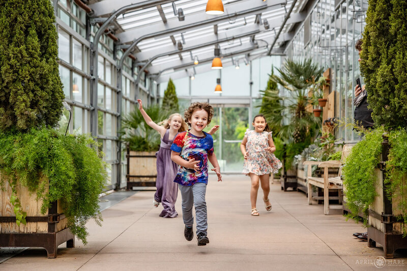 Kids run inside the Orangery at a  greenhouse wedding reception at Denver Botanic Gardens