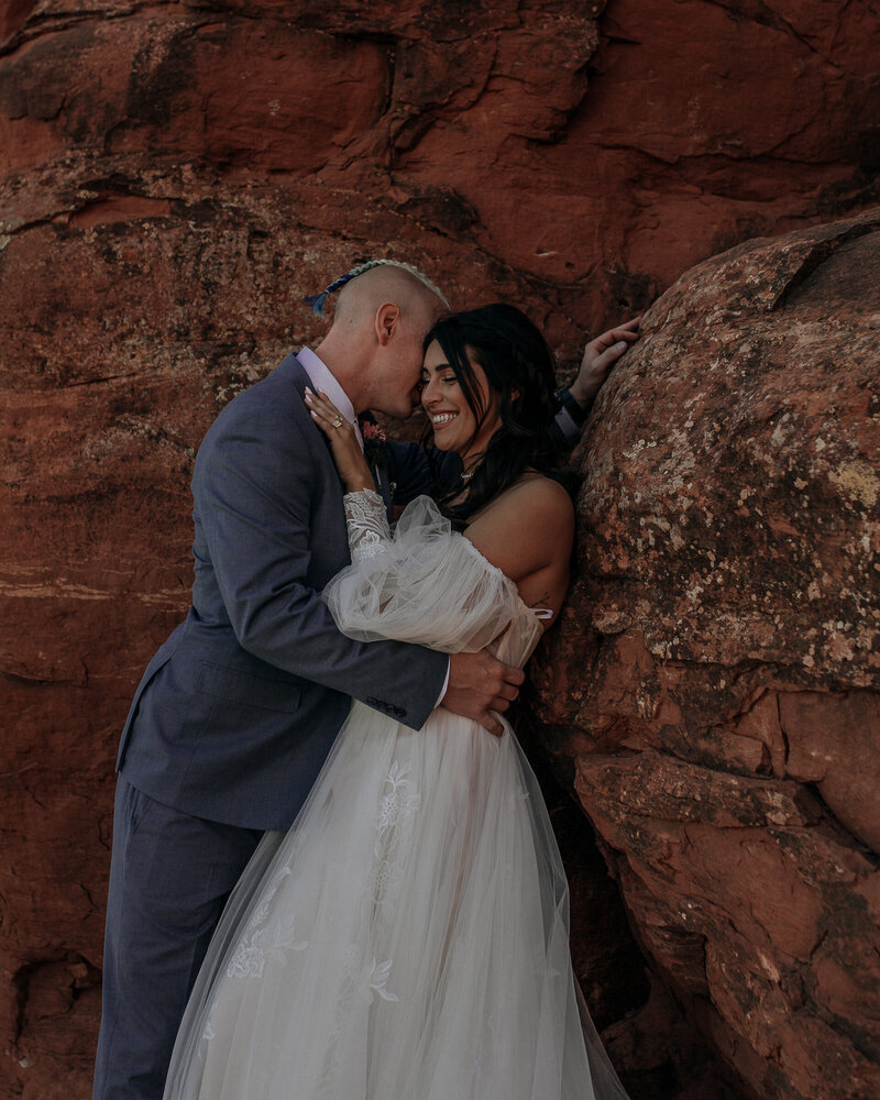 bride and groom laughing together in the red rocks of arizona