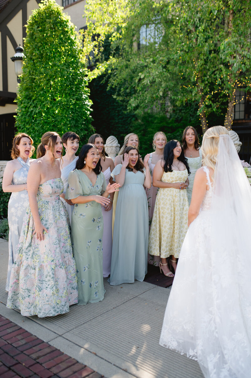A group of bridesmaids standing in front of the bride that has her back towards the camera. 