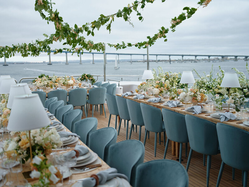 Our Ocean Blue Velvet Dining Chairs with our Burl Wood Dining Table and our Brass Table Lamps all set up on a yacht in the San Diego Harbor.   