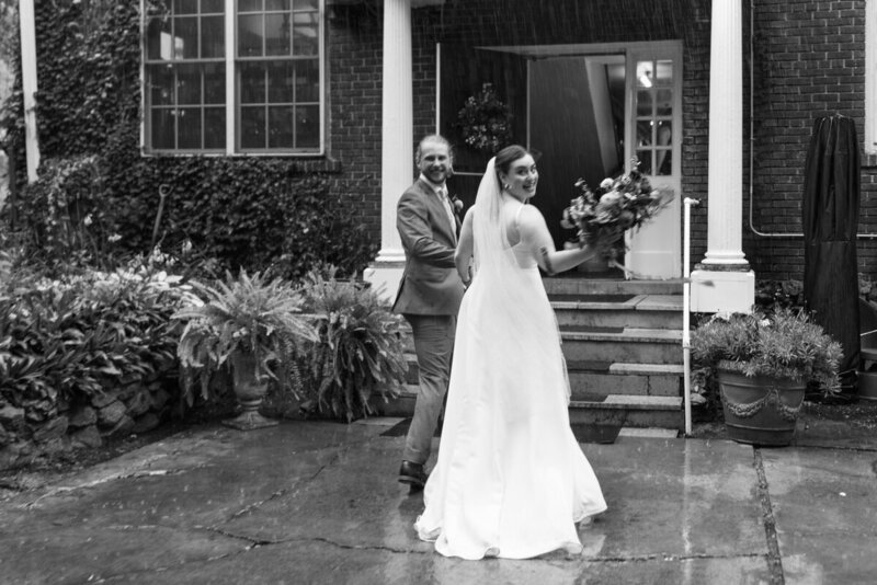 black and white photo by tom thornton photography in st paul minnesota of bride and groom on their wedding day looking back as they walk toward rainy stairs