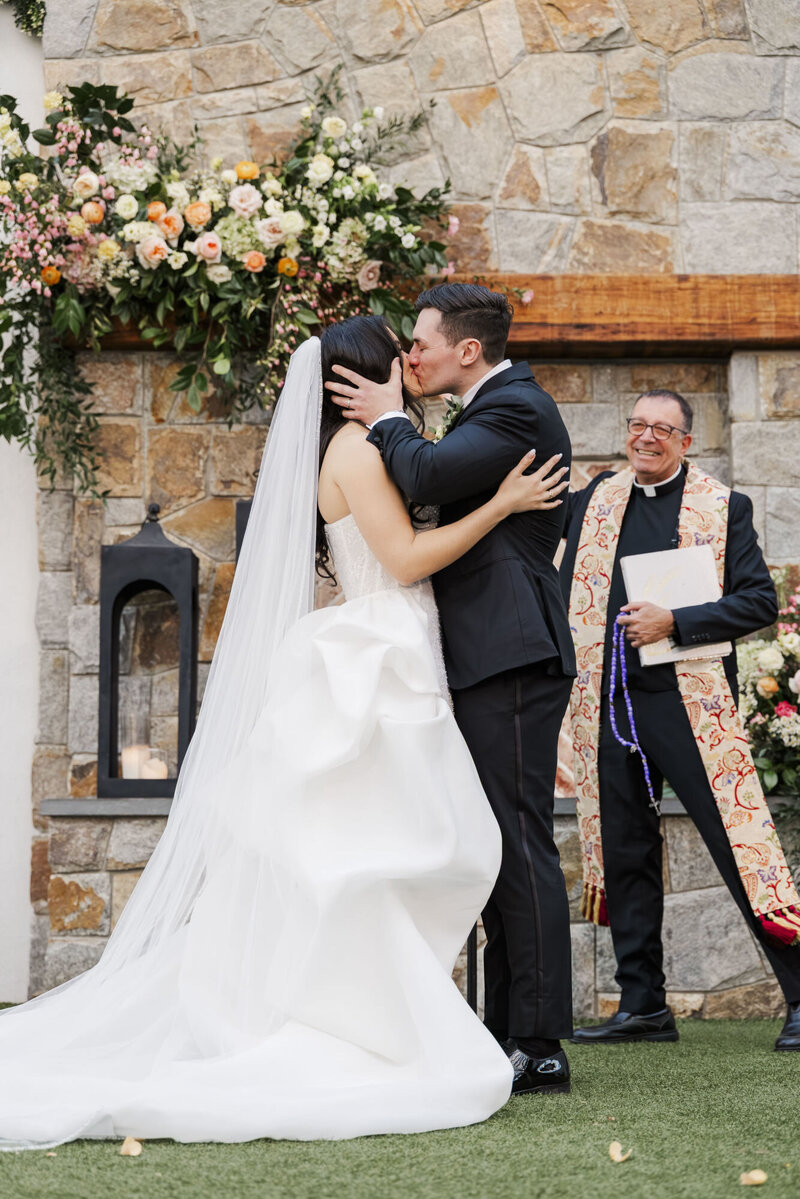 Shanna and John sharing their first kiss as their officiant beams beside them
