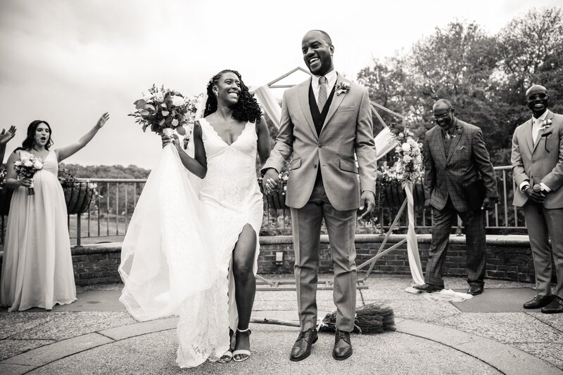 Two newlyweds jump over a broom during their ceremony