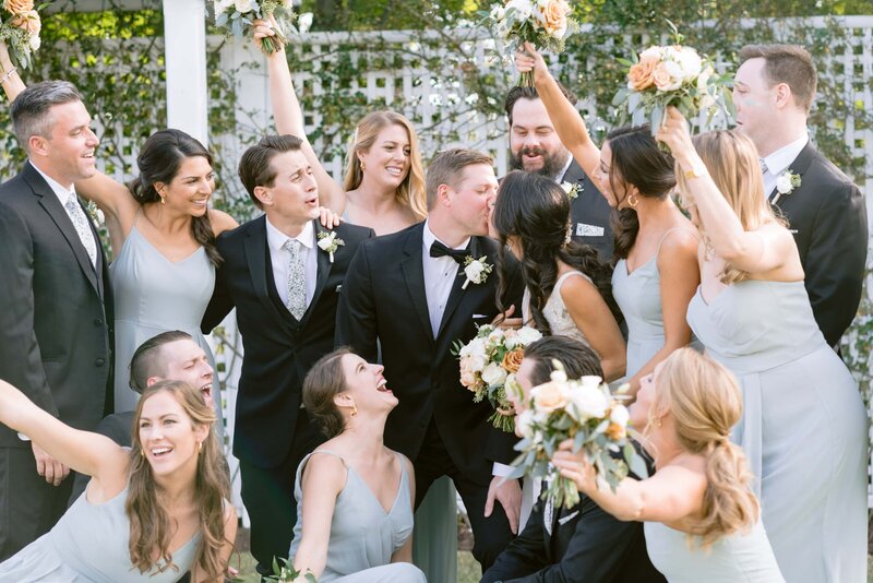 Bride and groom kiss cheered on by bridal party