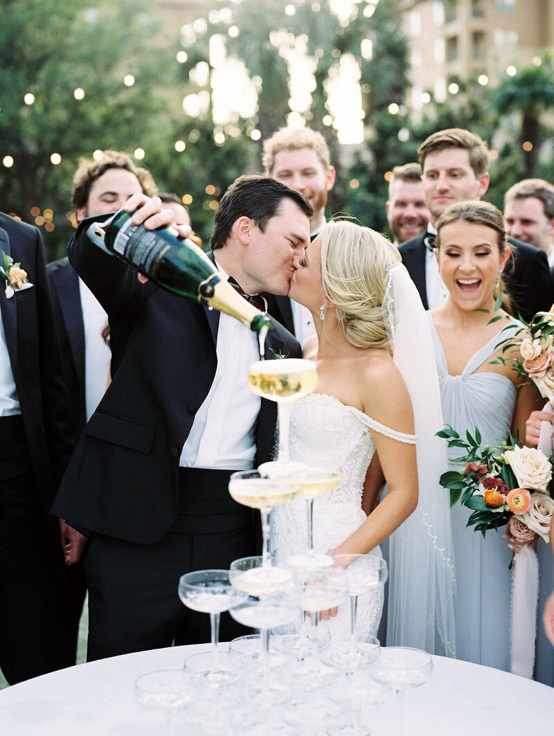 Bride and groom kissing while pouring a champagne tower
