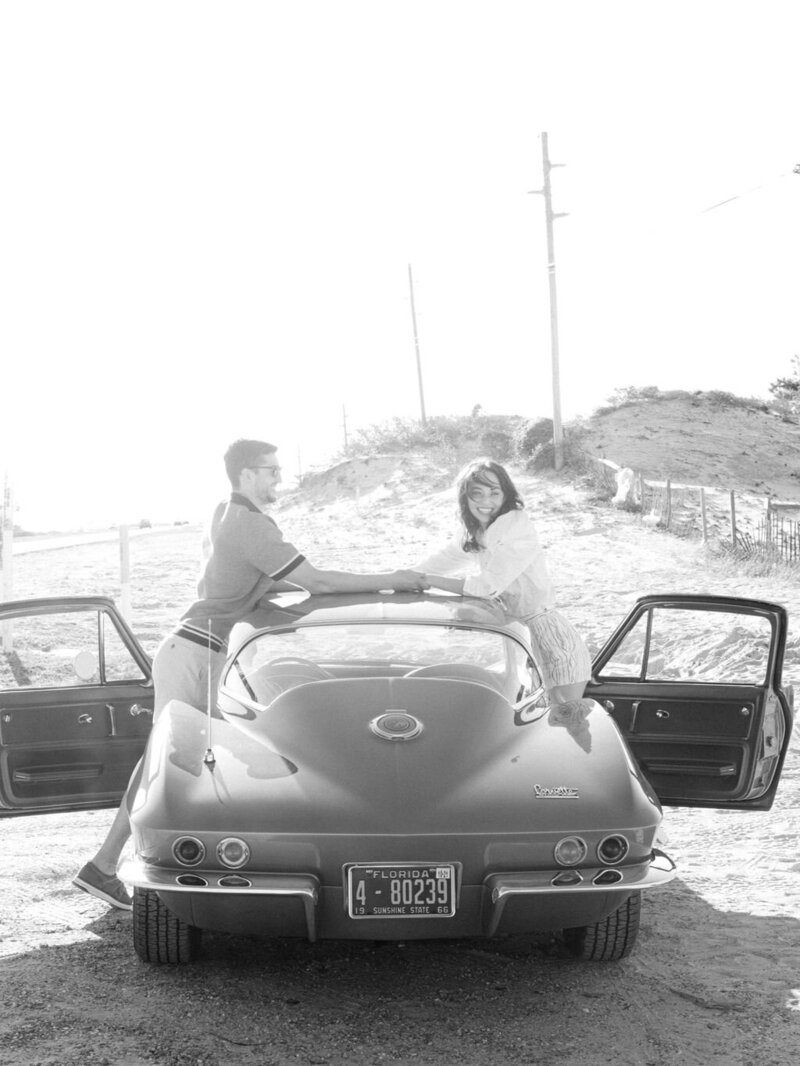 couple holding hands above the roof of a sports car at Kaiya beach