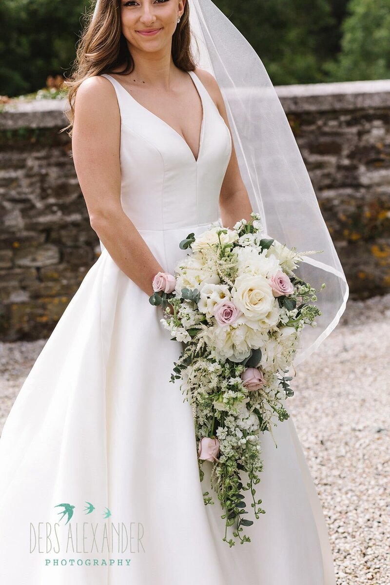 A bride wearing a satin dress with a cascading bouquet of flowers 