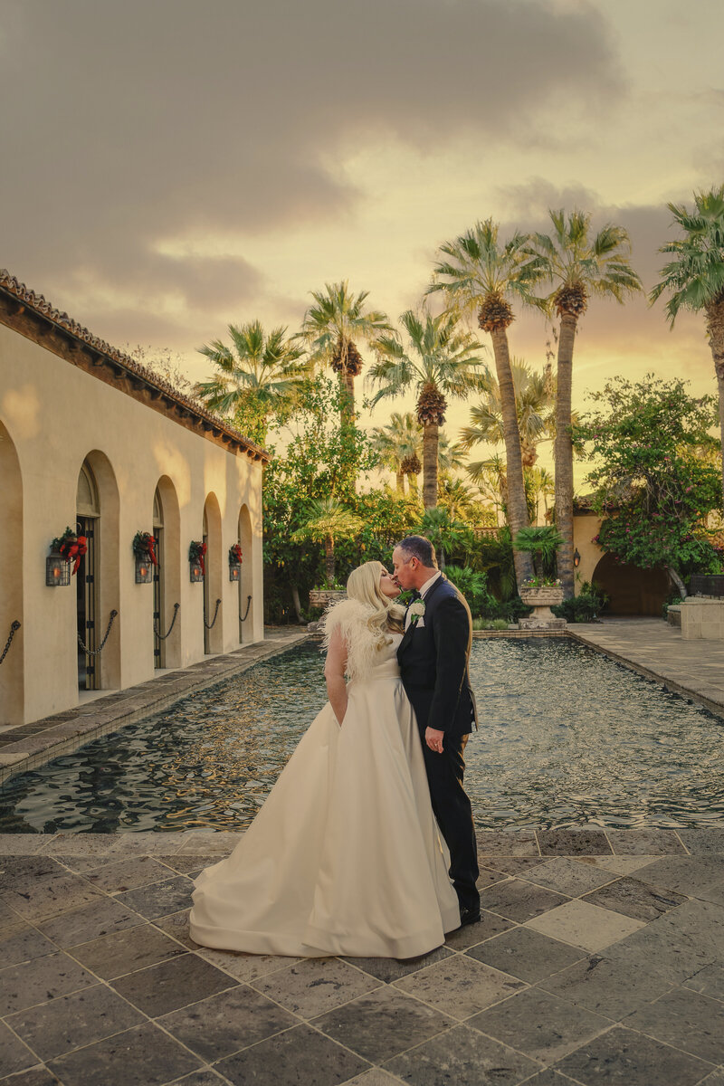 Bride and groom embrace on elaborate curved staircase