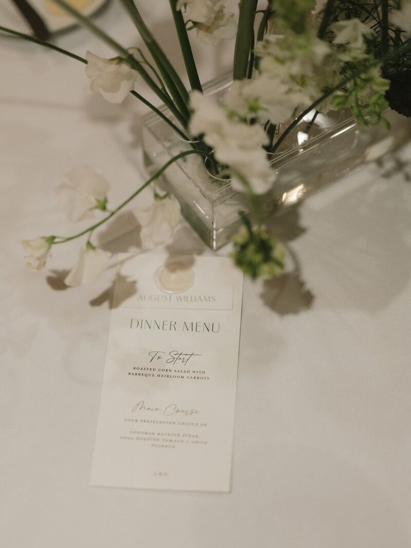 Close-up of a wedding menu with white flowers, representing luxury wedding photography details.