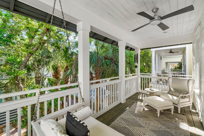 Comfortable front porch with lounge chair, ottoman, and tropical landscaping in view