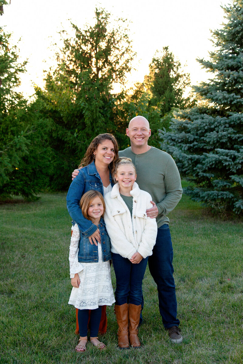 Photographer Janelle Reule smiling with her husband and two girls. 