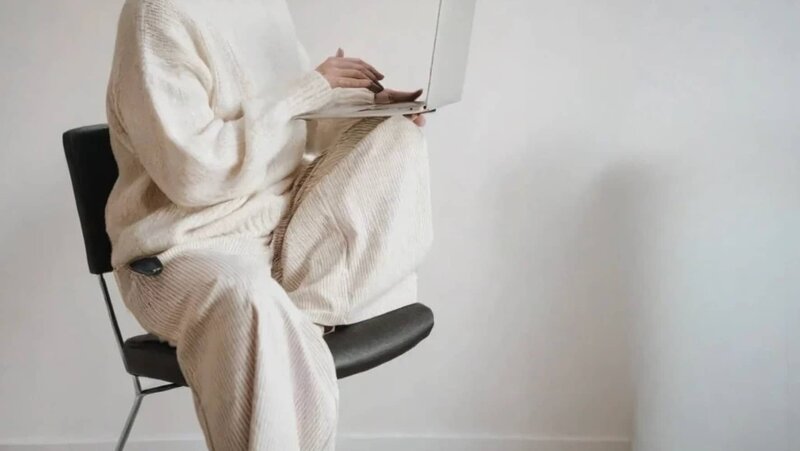 Person i stickad outfit med laptop i knät – en trygg start på resan bort från medberoende.