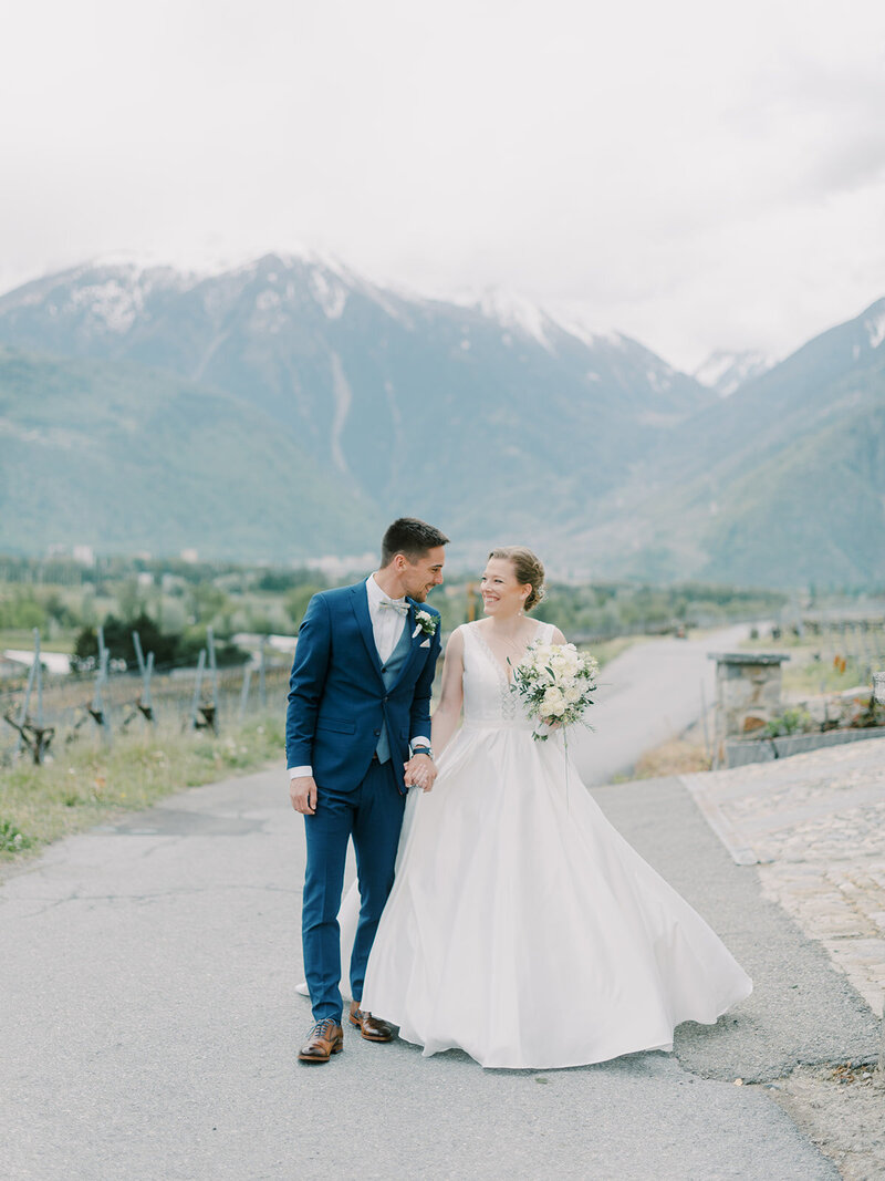 A-bride-and-groom-standing-on-a-road-with-mountains-in-the-background