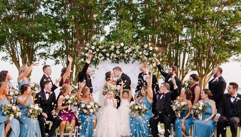 A joyful destination wedding ceremony with the bride and groom kissing and guests cheering.