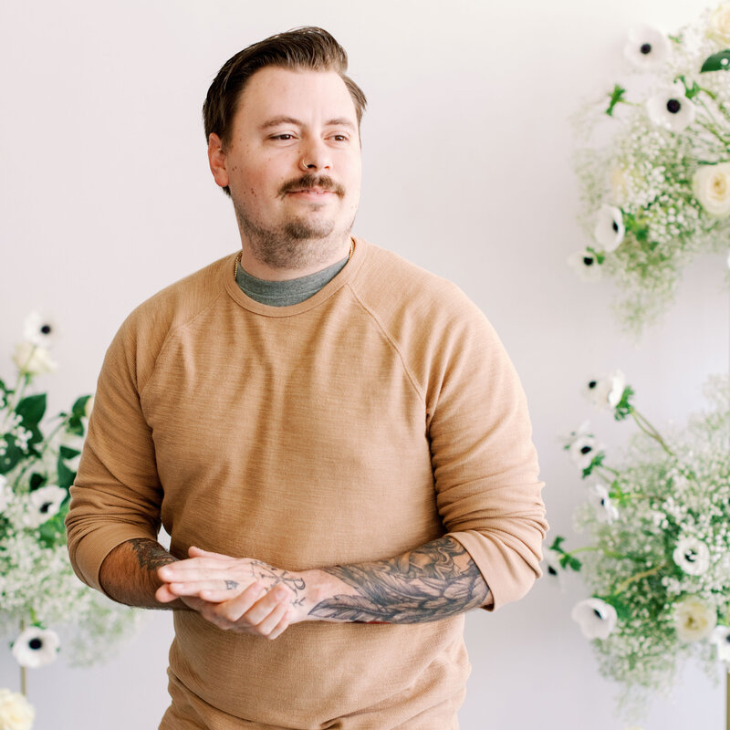 Jesse smiling and looking off camera with floral detail background