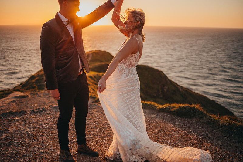 bride and groom twirl by the ocean during sunset