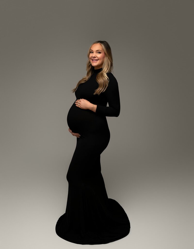 Confident maternity portrait in a long black gown with train and sleeves