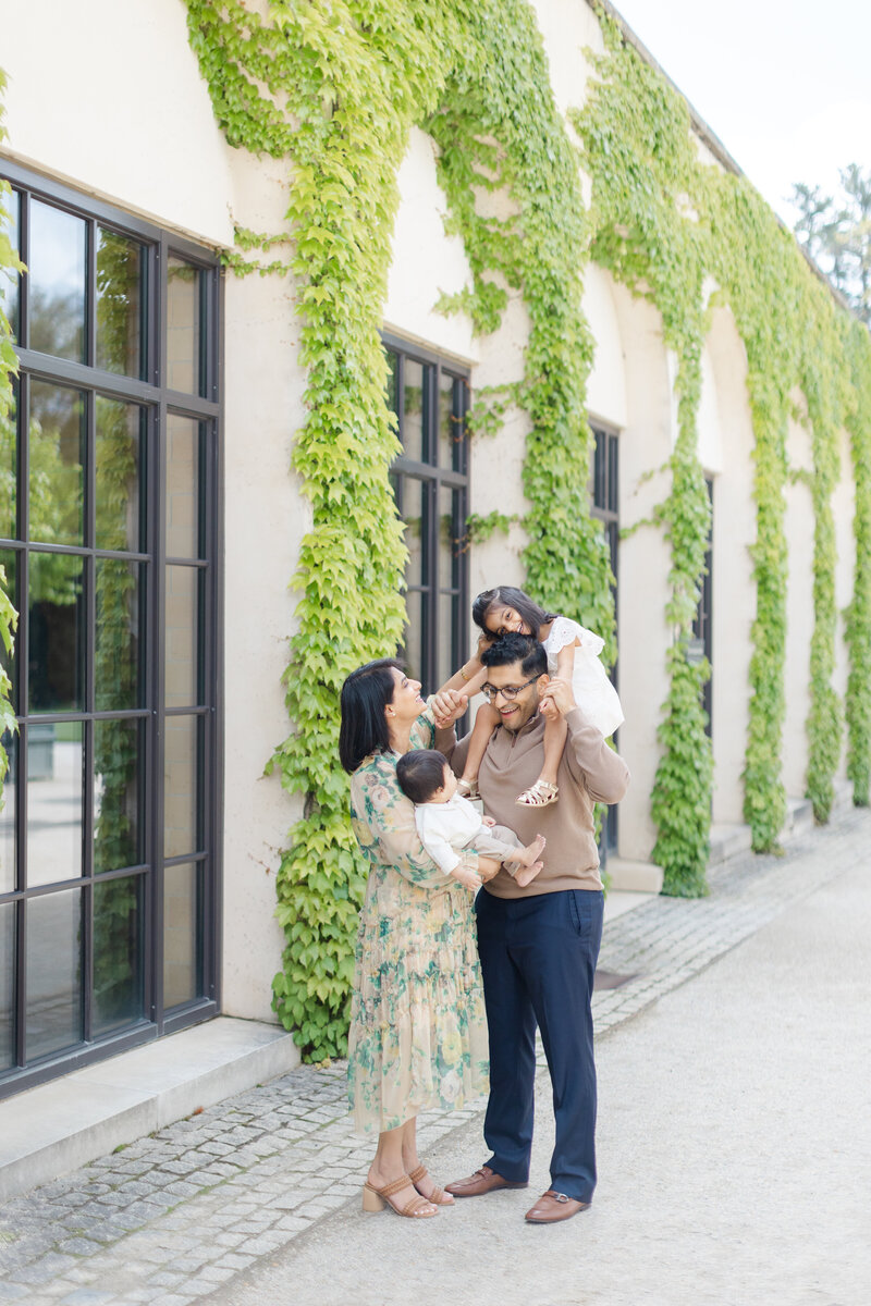 Mother and father carry their young daughters during outdoor portrait session