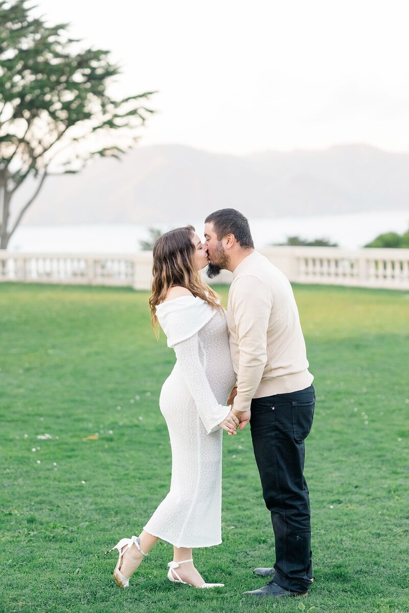 expectant parents kissing on the lawn of legion of honor