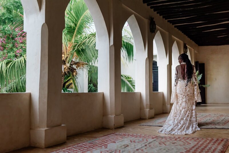 A bride in a gorgeous detailed lace gown walks through a Morroco style open air home during an adventure luxe destination elopement with her traveling photographer. 