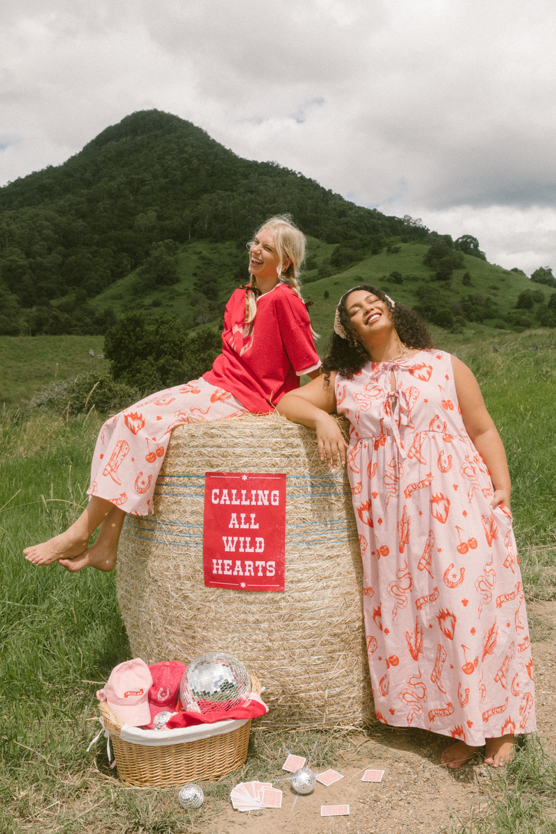 Two models posing for fashion brand with a hay bale.