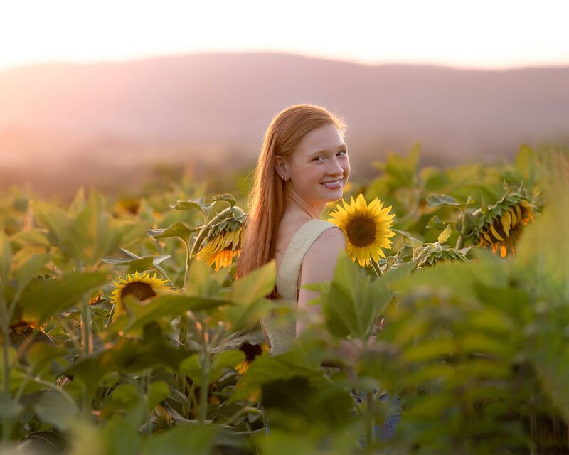red haired girl in sunflower field at sunset