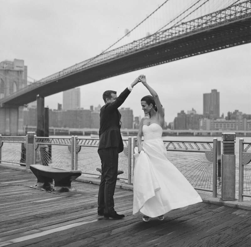 Rachel and Jim dancing on the pier beneath the Brooklyn Bridge