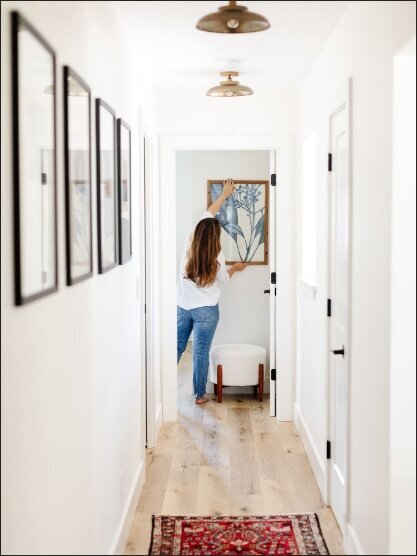 Designer hanging up frame in white hallway