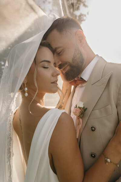 Mariée dans les bras de son chéri en costume beige avec effet de voile. Projet de mariage imaginé par Nos Moments Ensemble, agence évènementielle Nantes Loire Atlantique Vendée.