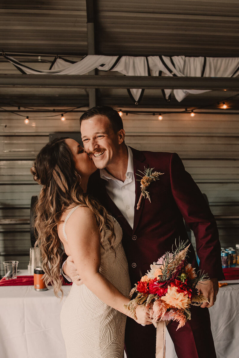 A person kissing their partner's cheek as they smile 