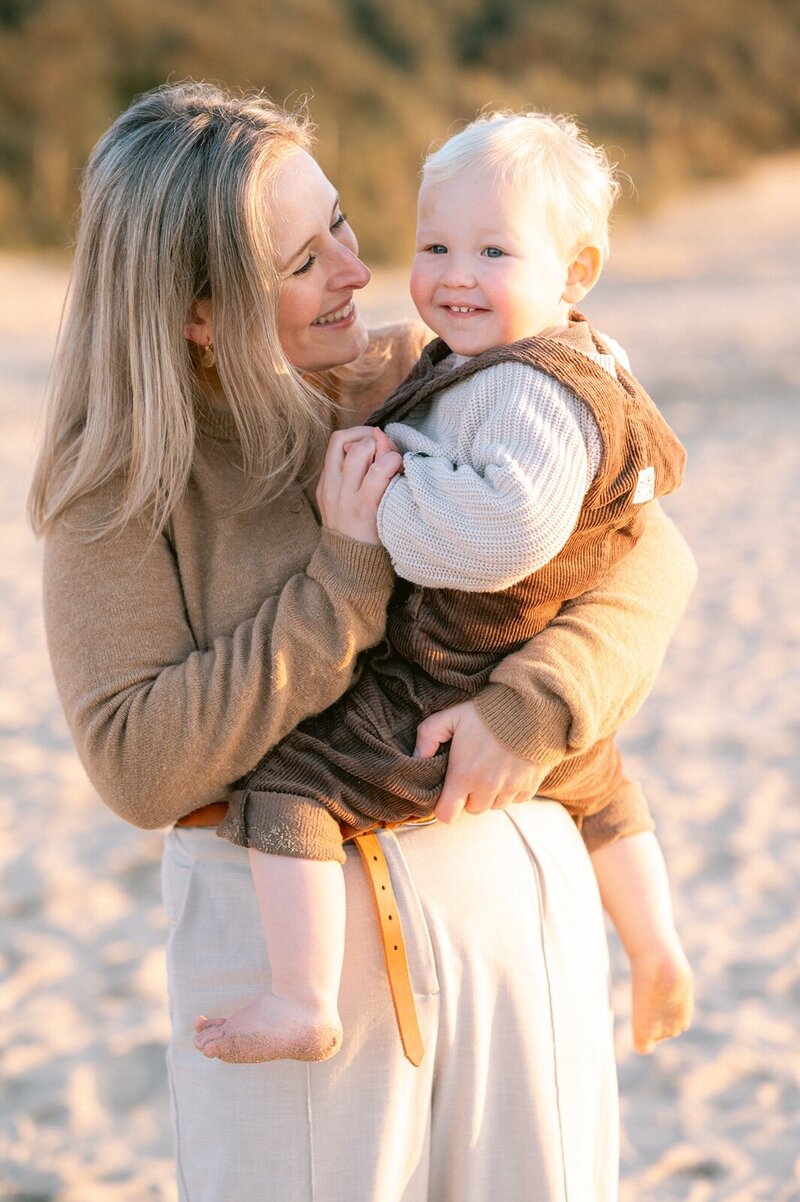 Moeder met zoontje knuffelt op het strand in Katwijk aan Zee