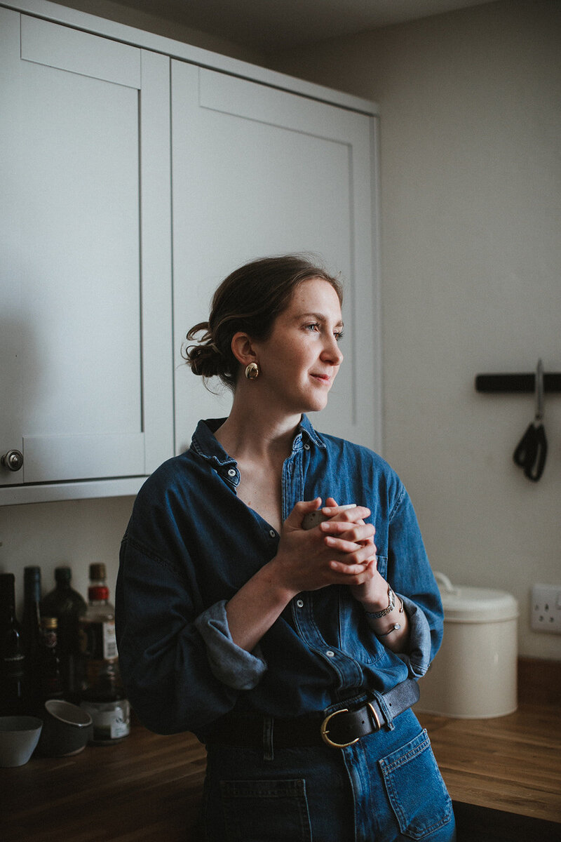 Copywriter reflects in her kitchen over a cup of coffee 