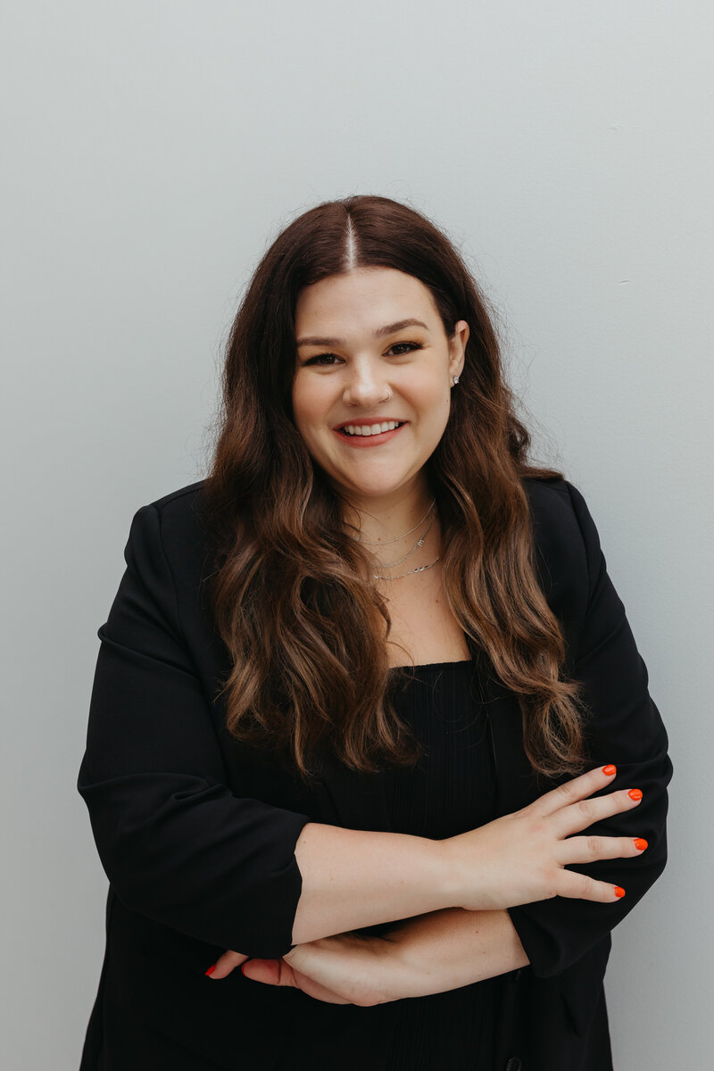 Headshot of woman in a black blazer with her arms crossed