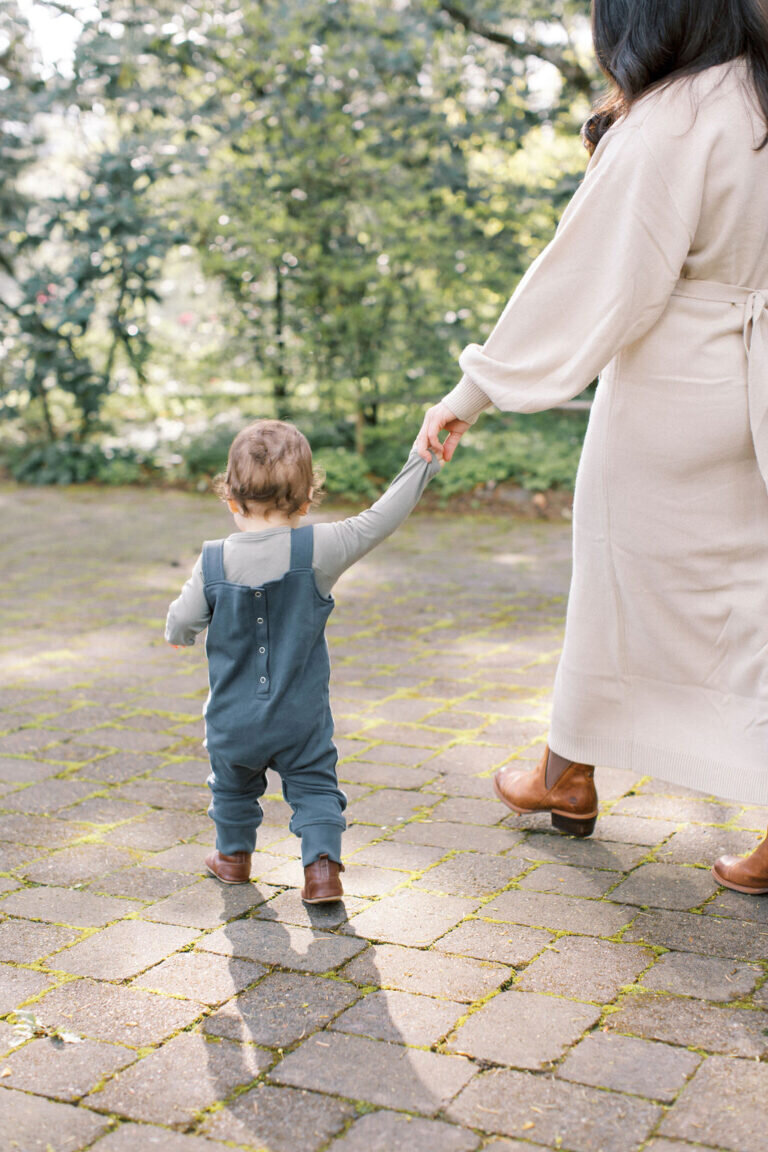 mom holds child's hand while walking in the sun