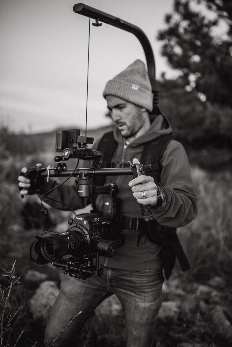A black and white image of a Future Fox Media team member adjusting video equipment on set, showcasing the dedication and expertise involved in crafting compelling video content. This shot reflects the creative energy driving Denver’s leading video marketing agency.