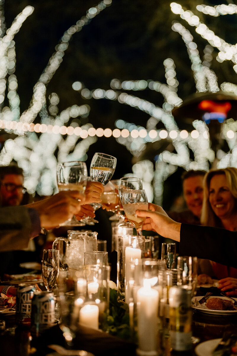 guests toast at table under string lights