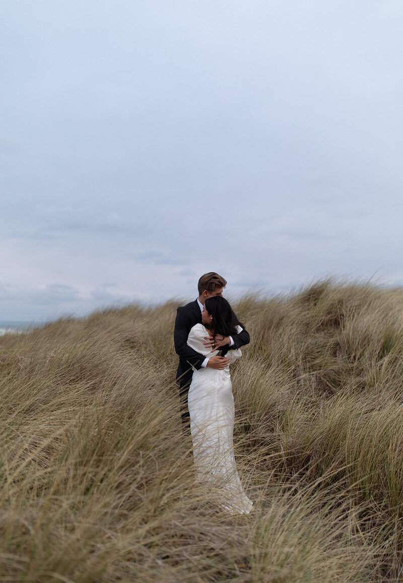 Bride and groom embracing in tall golden grass during an intimate Utah elopement.