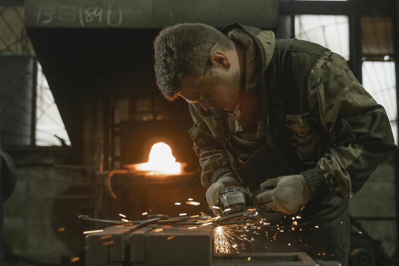 Frontline industrial worker welding metal, representing hands-on leadership and skilled execution