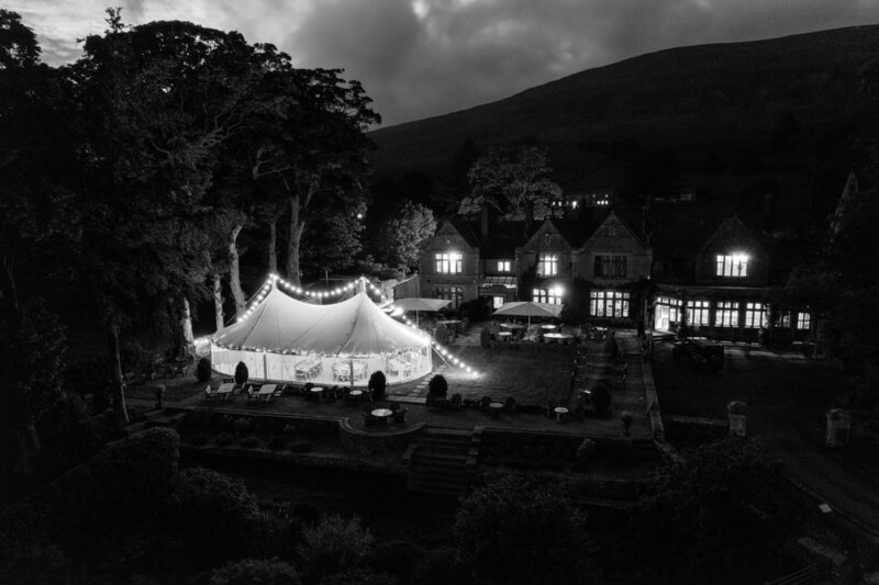 A black and white image of a pole marquee on beautiful grounds, taken from the air looking down