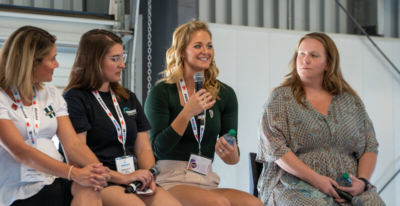 woman sitting in stools on a stage speaking to an audience