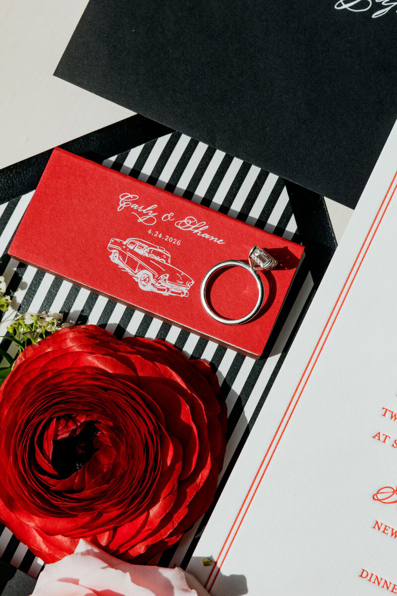 Red ranunculus resting on a striped invitation suite