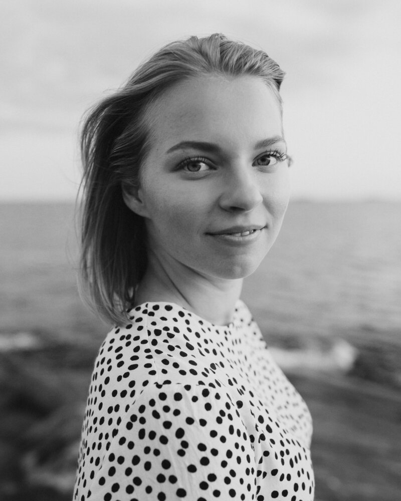 Henkilökuva naisesta, joka seisoo rantakalliolla ja katsoo hymyillen kameraan Suomenlinnassa Helsingissä