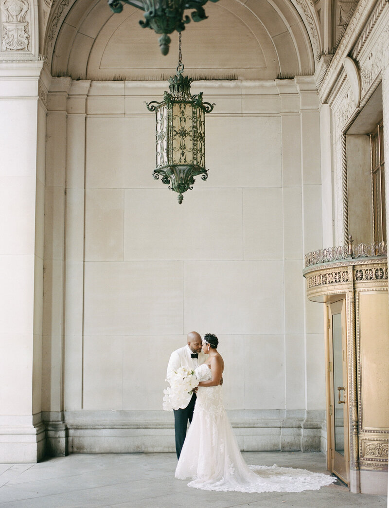 black wedding in Detroit with beautiful architecture, groom white tux, bride lace mermaid dress
