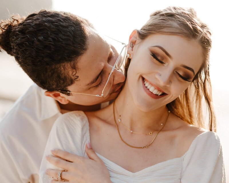 a man kissing his fiance on the neck