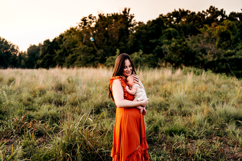 mom holding newborn in a field