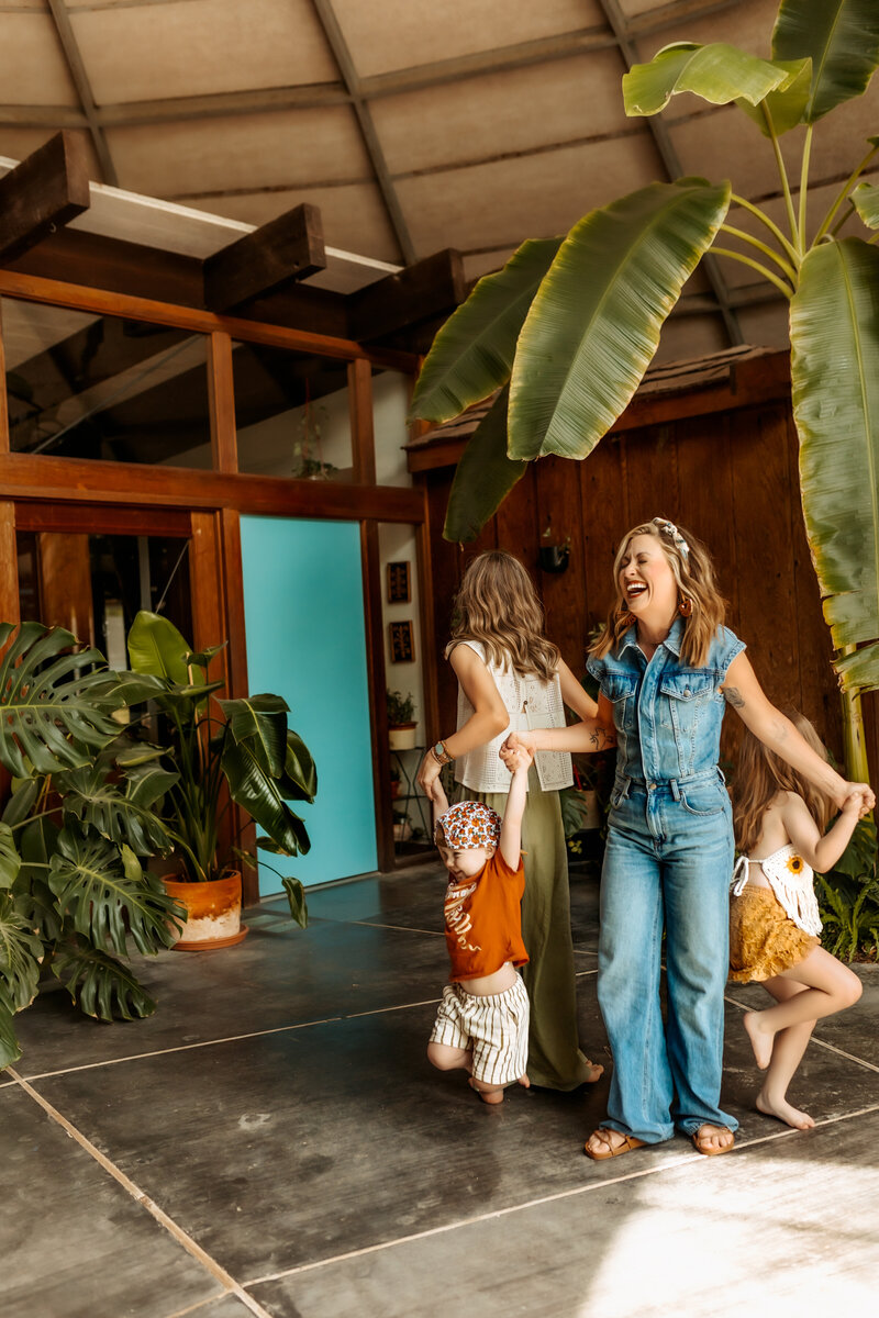 Kansas City Family Photographer captures mom doing reverse ring around the rosie with her three children in greenhouse.