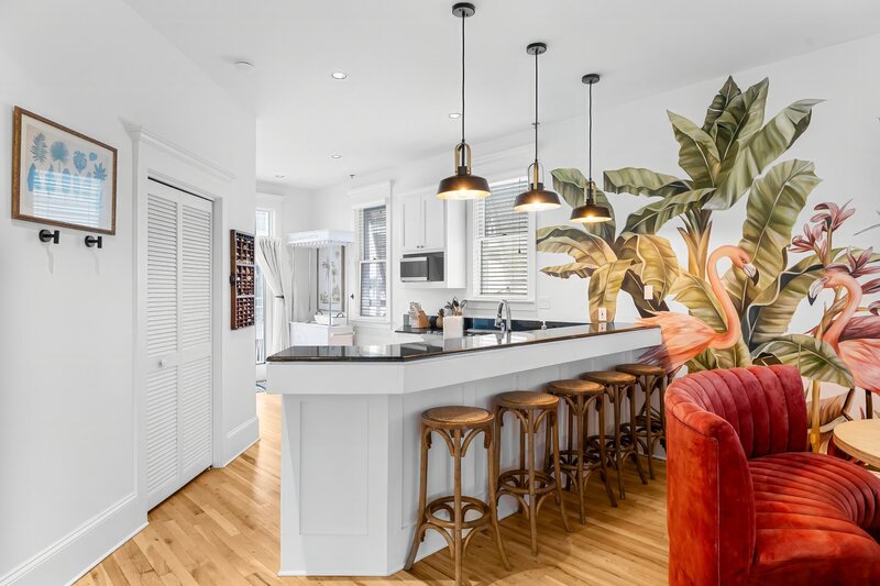 Chic coastal kitchen with vibrant flamingo mural and breakfast bar seating at The Florida House, a Carillon Beach house rental near Panama City Beach and 30A.