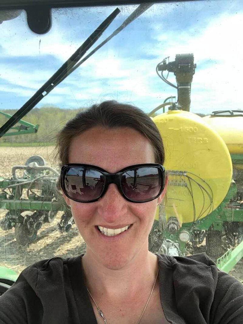 Jess riding a tractor through a field