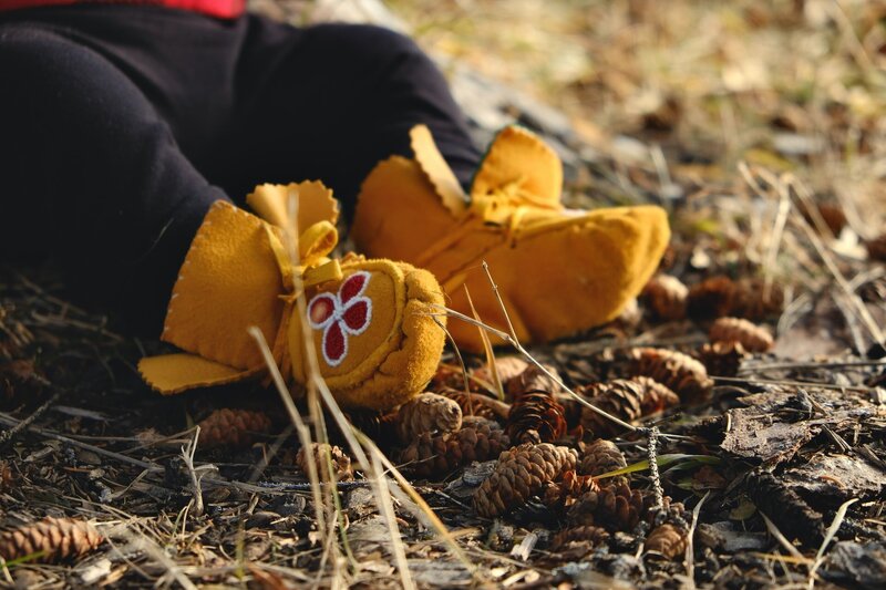 Moccasins on baby's feet outdoors in nature