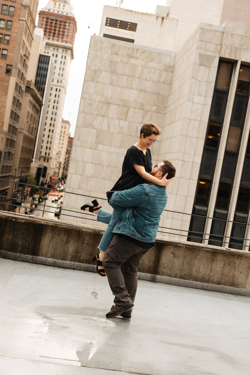 Couple captured in a romantic moment in a downtown setting, surrounded by city streets.